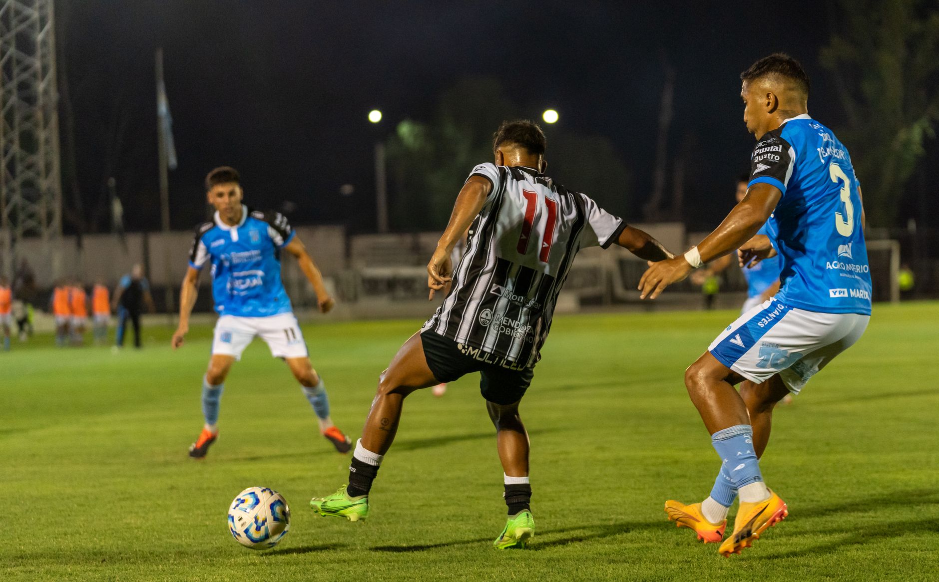 football players competing for ball on field at night stadium
