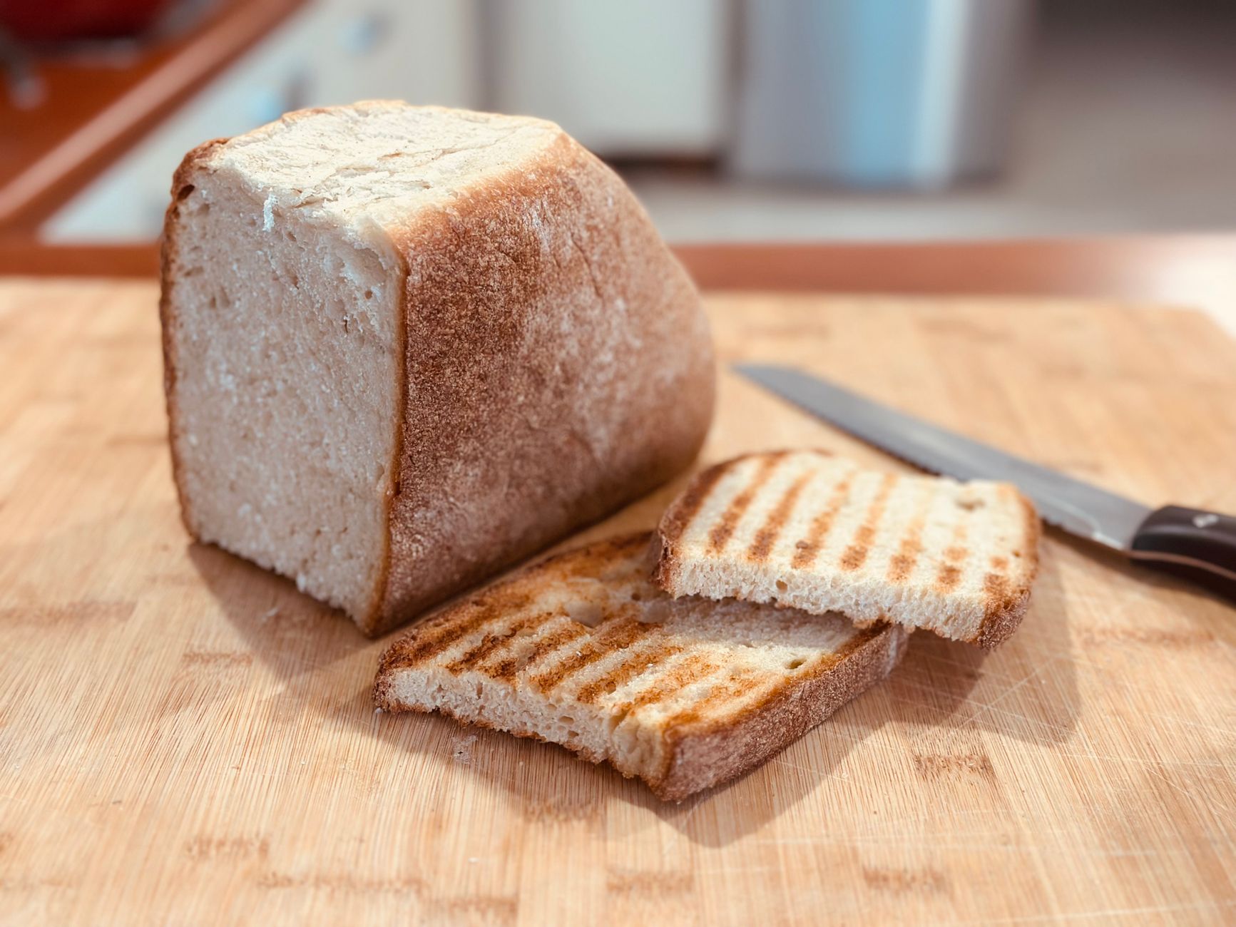 woman slicing artisan sourdough bread on wooden board