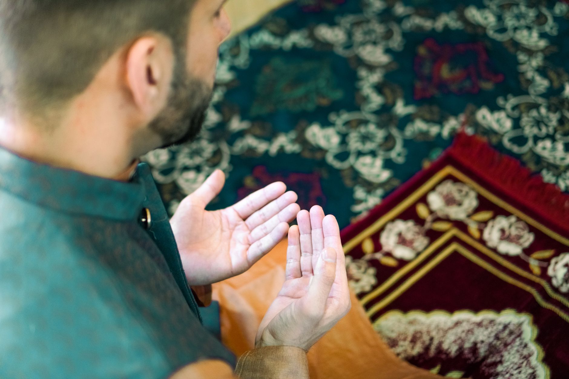 person praying with prayer mat at home