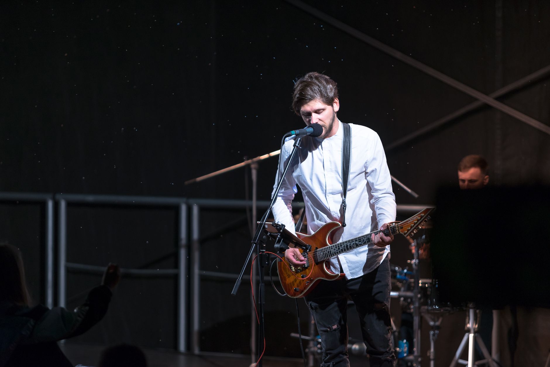musician playing guitar on stage with dramatic lights
