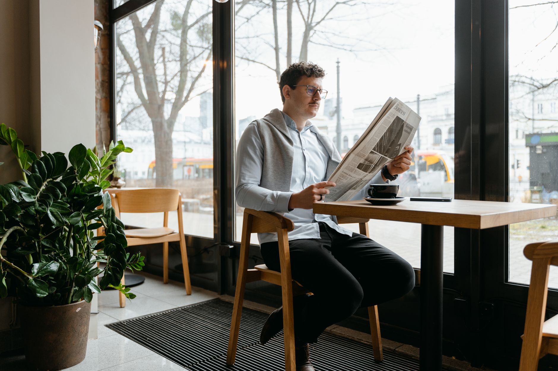 person reading newspaper about border conflict at cafe table