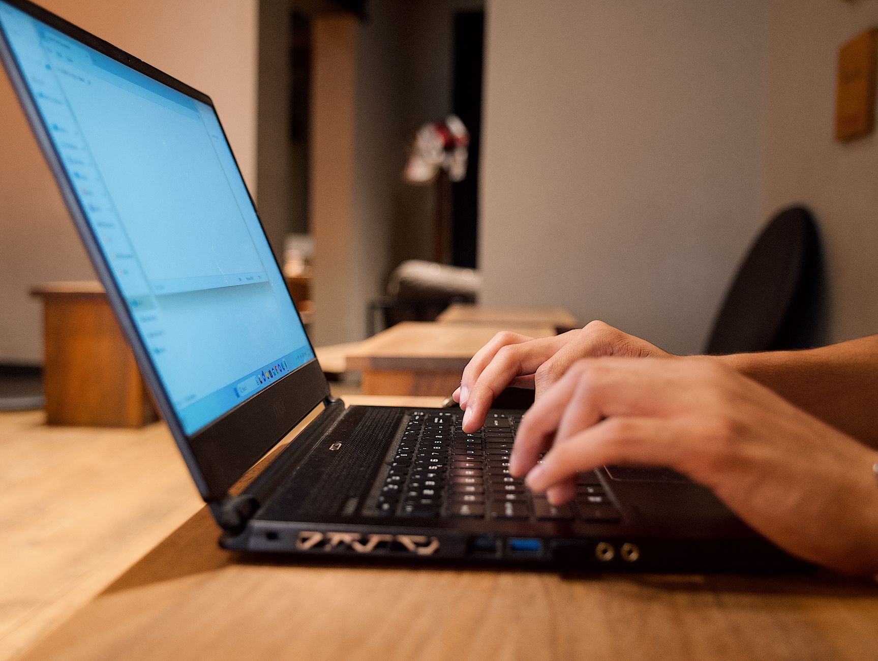 person typing on laptop keyboard in office