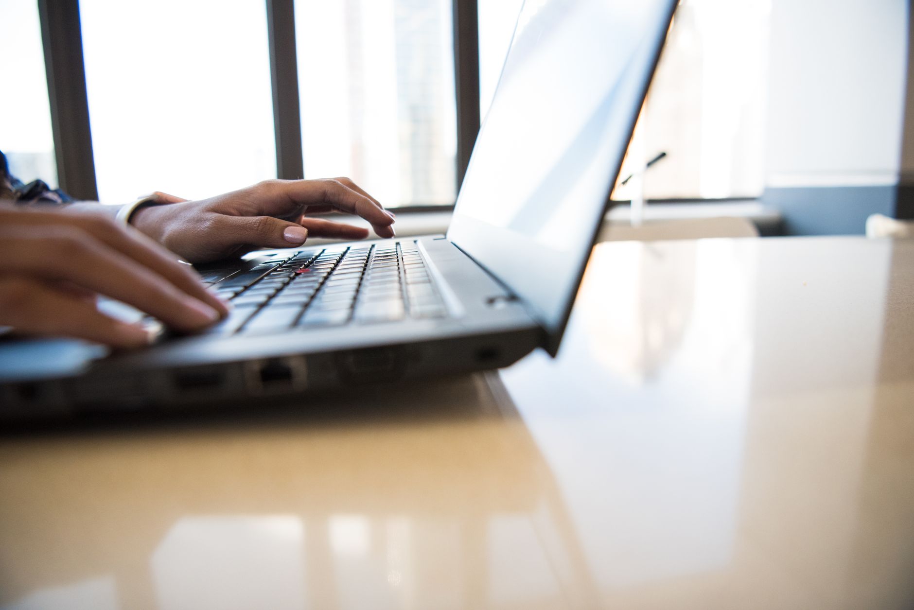 person typing on laptop keyboard in office