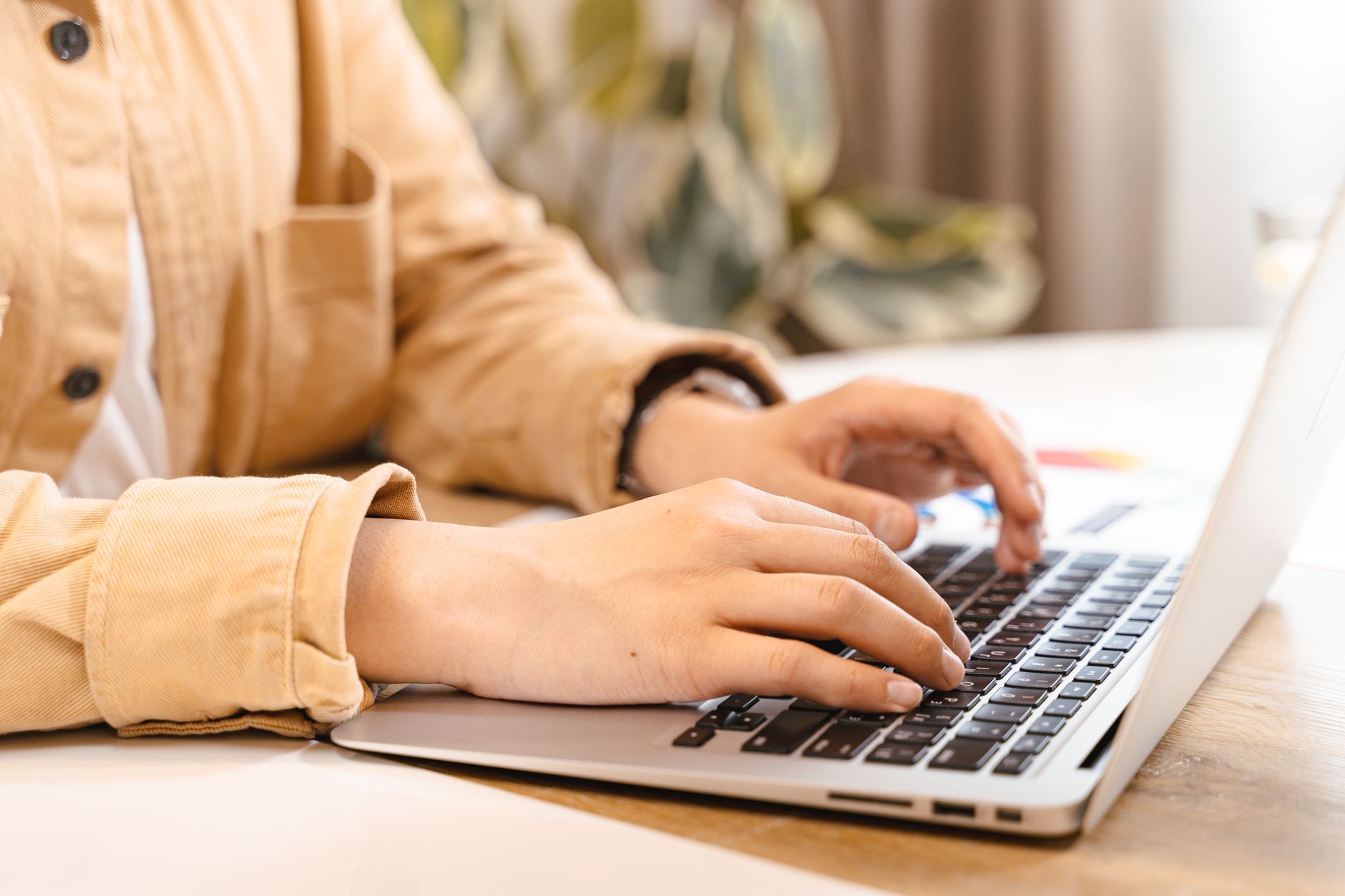 person typing on laptop keyboard in office
