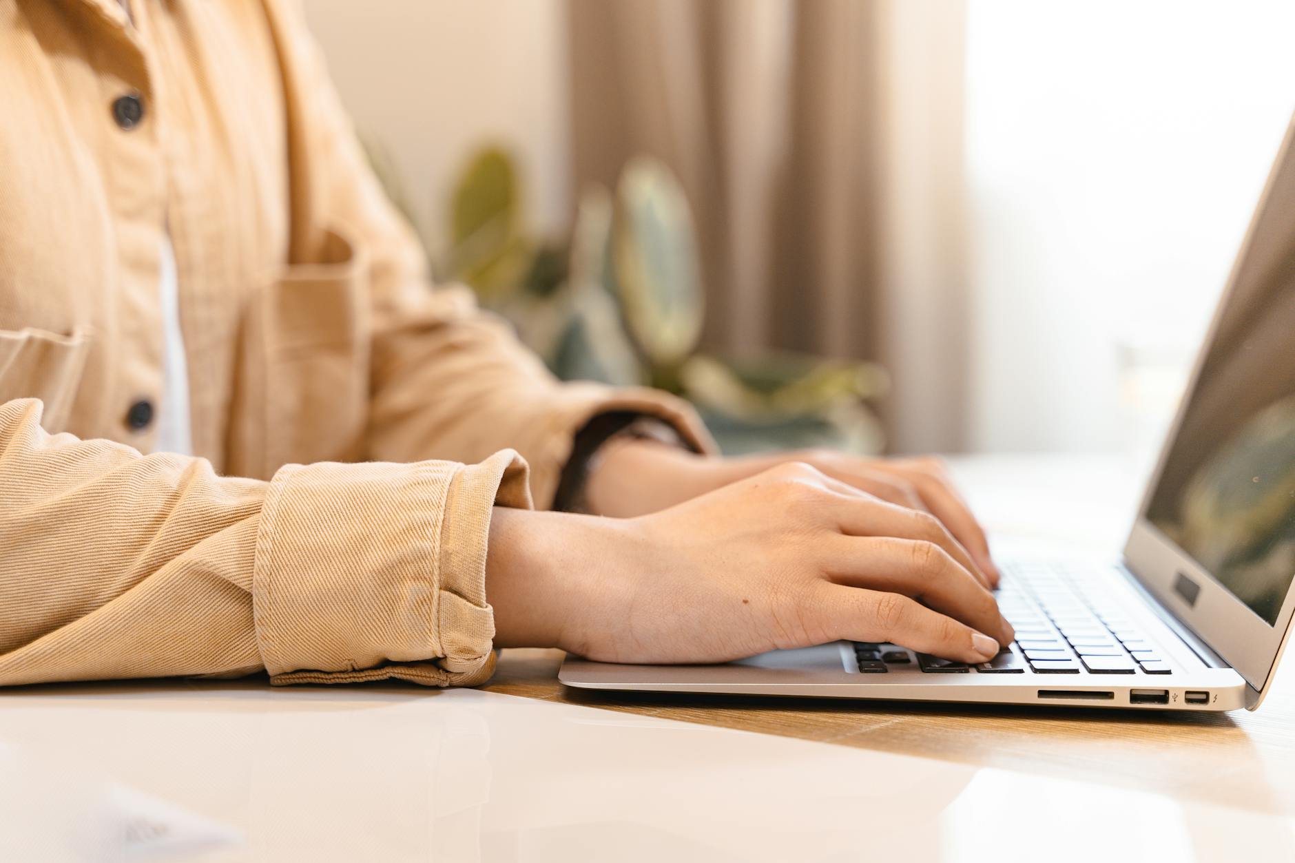 person typing on laptop keyboard in office