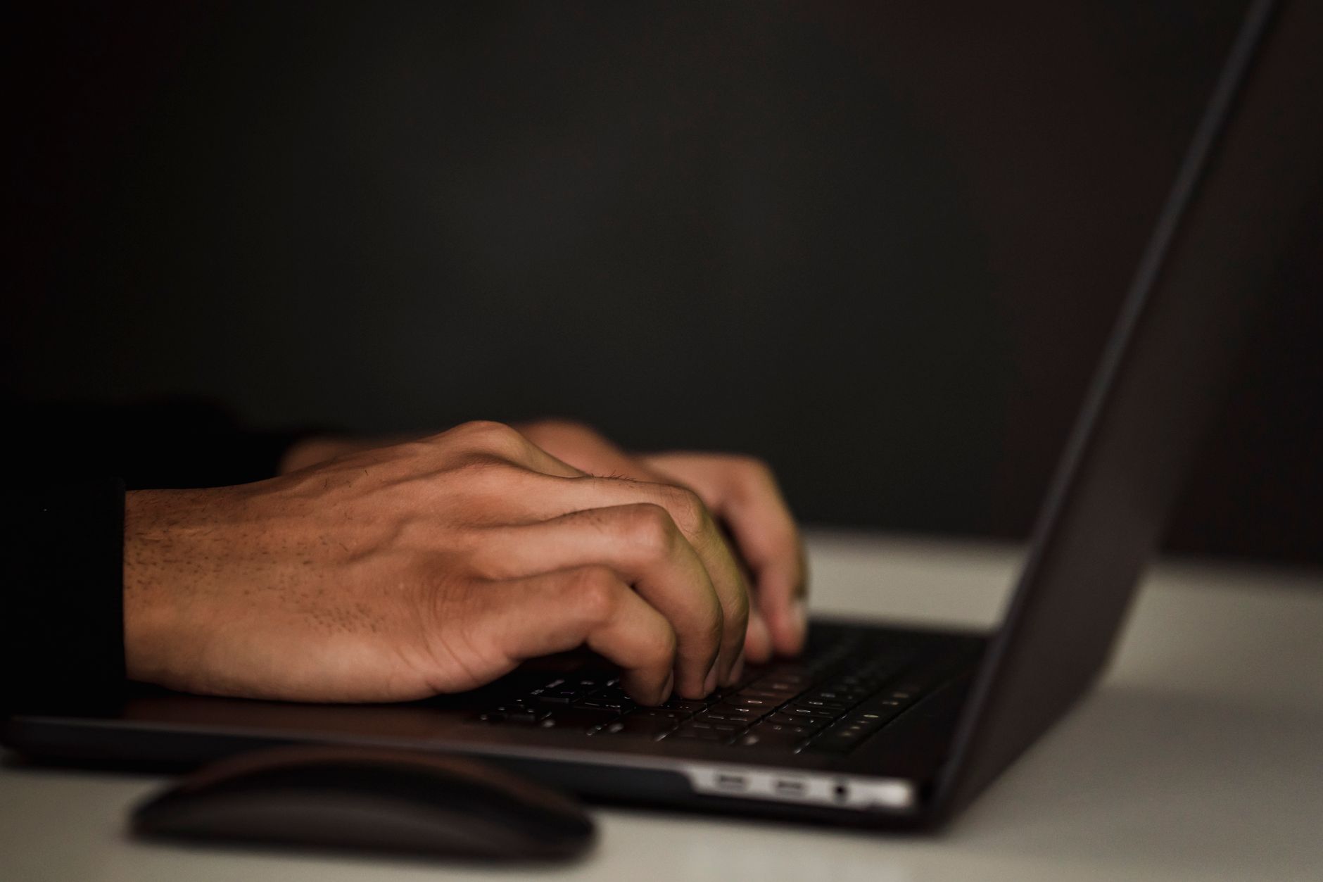 person typing on laptop keyboard in office