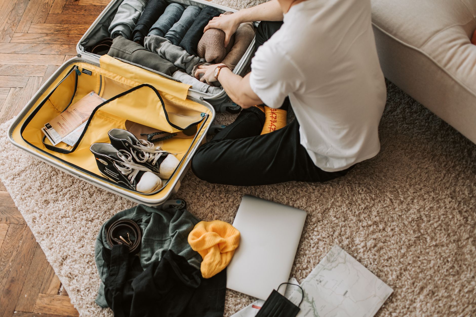 person packing travel essentials into open suitcase