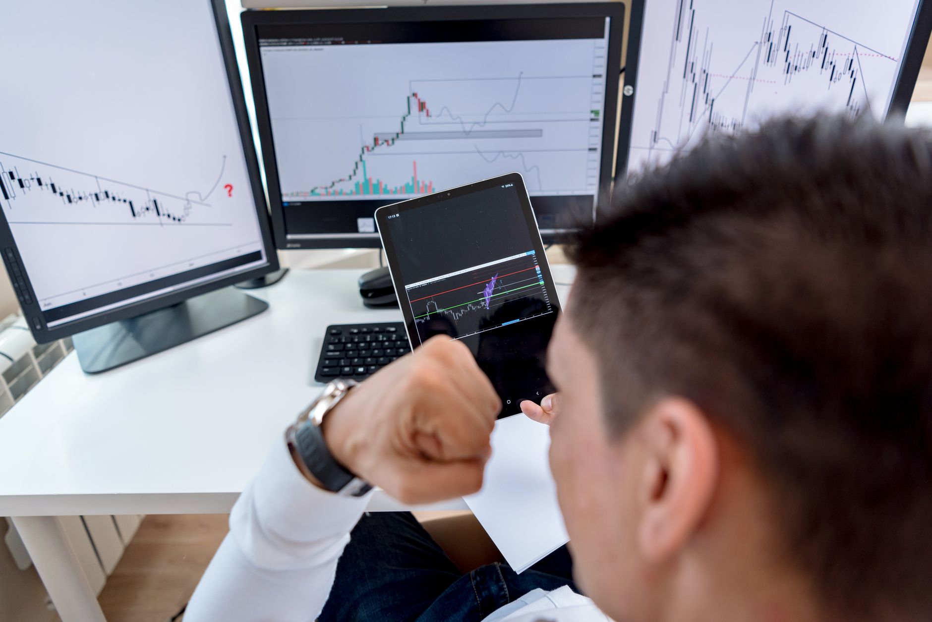 trader analyzing stock market graph on multiple screens