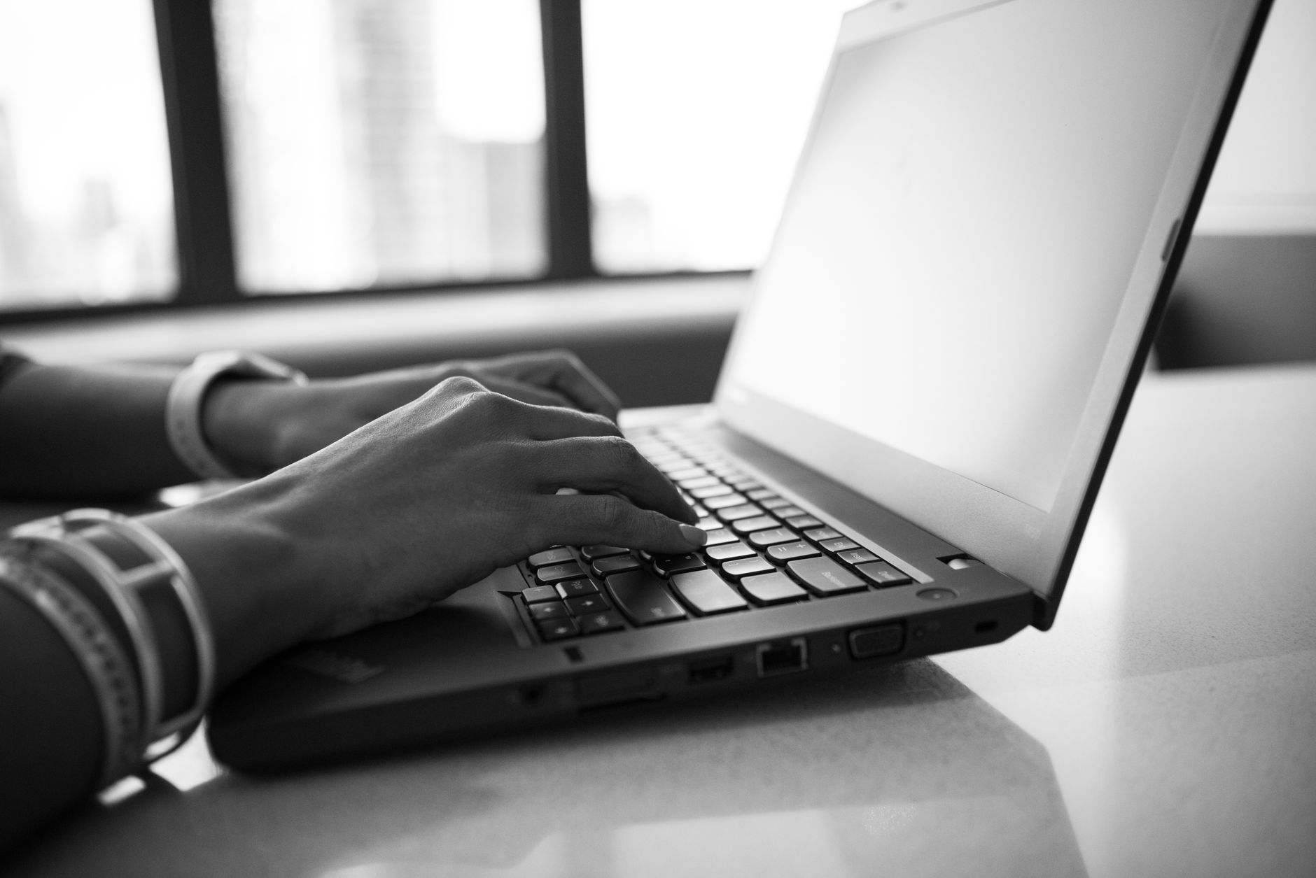 person typing on laptop keyboard in office