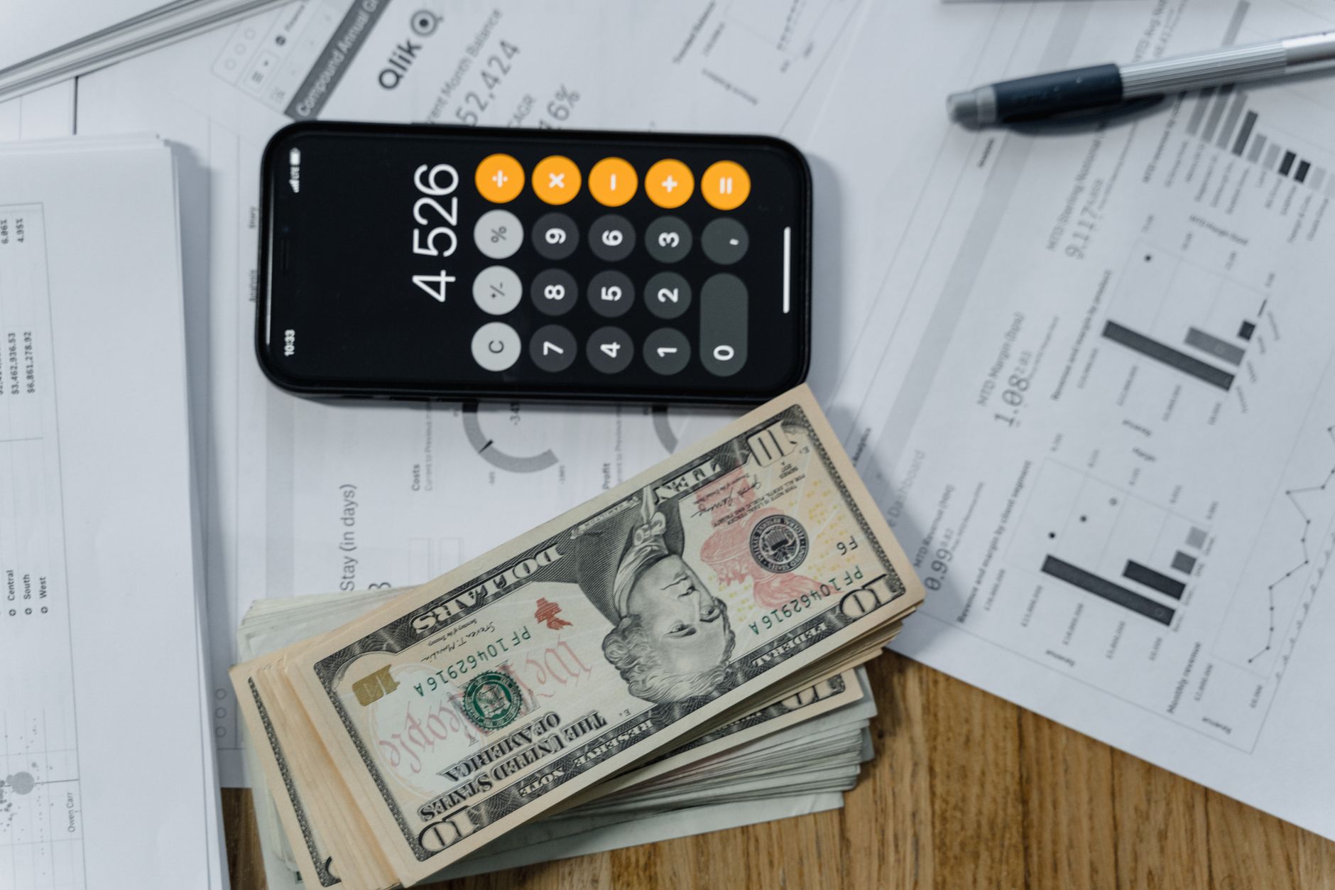 coins and bills stacked on calculator on wooden desk