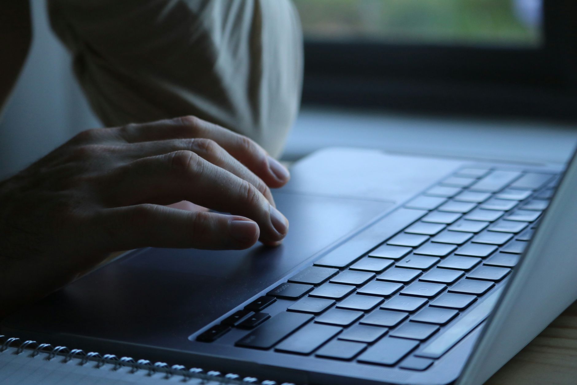 person typing on laptop keyboard in office