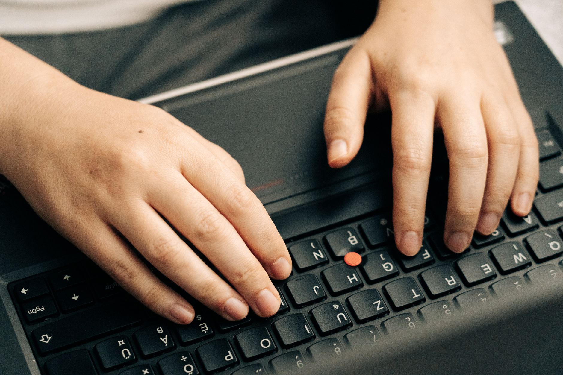 person typing on laptop keyboard in office