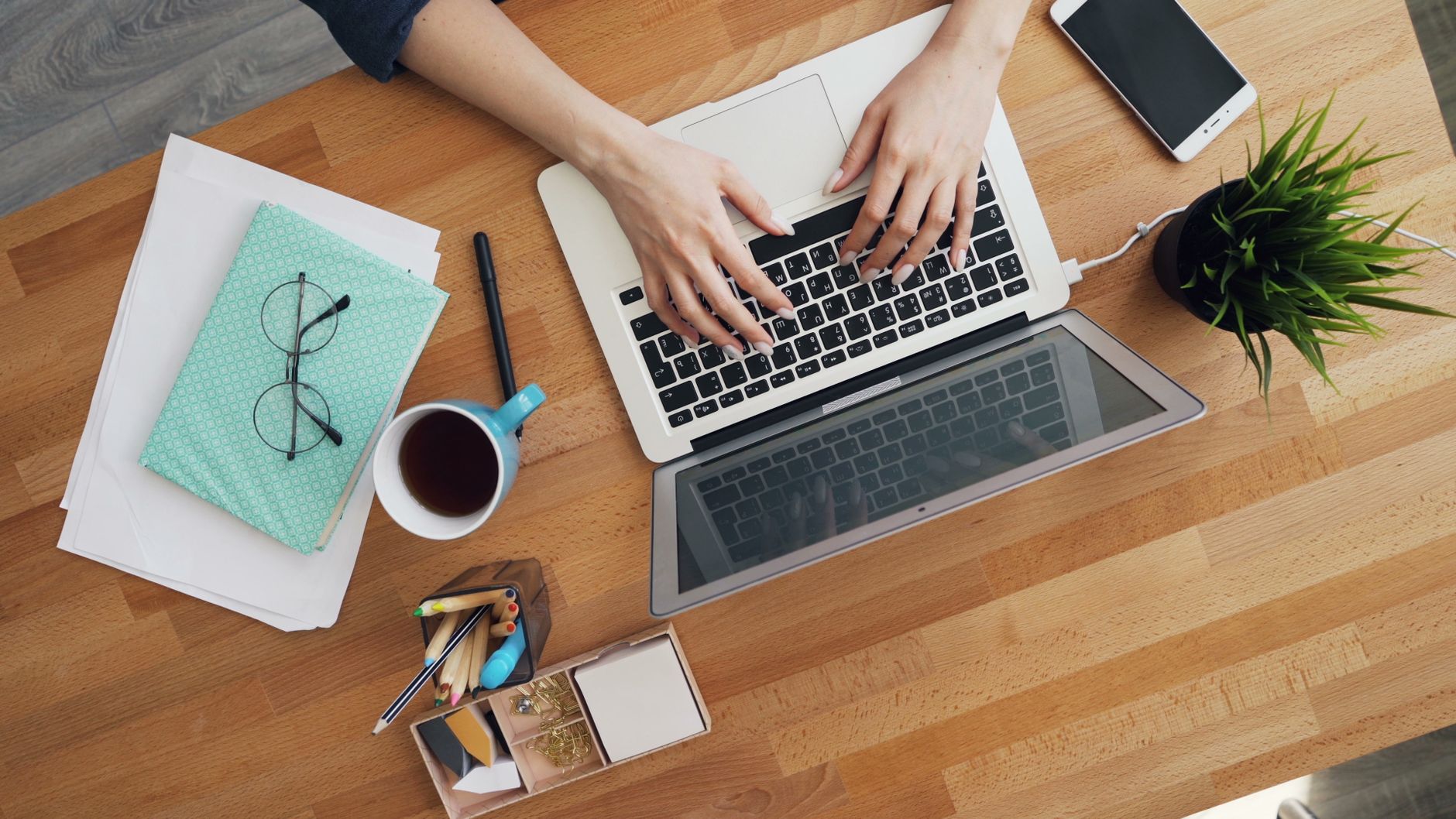 person typing on laptop keyboard in office