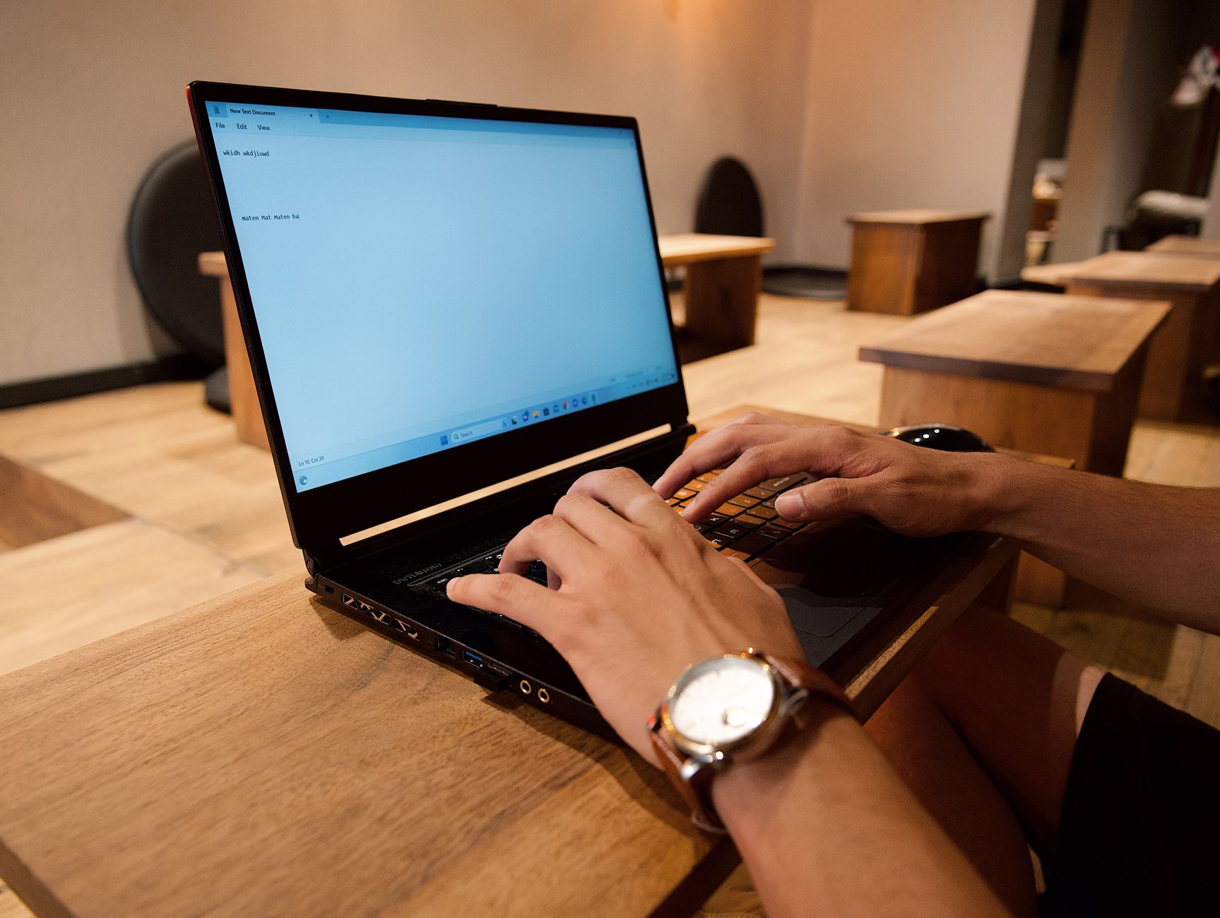 person typing on laptop keyboard in office