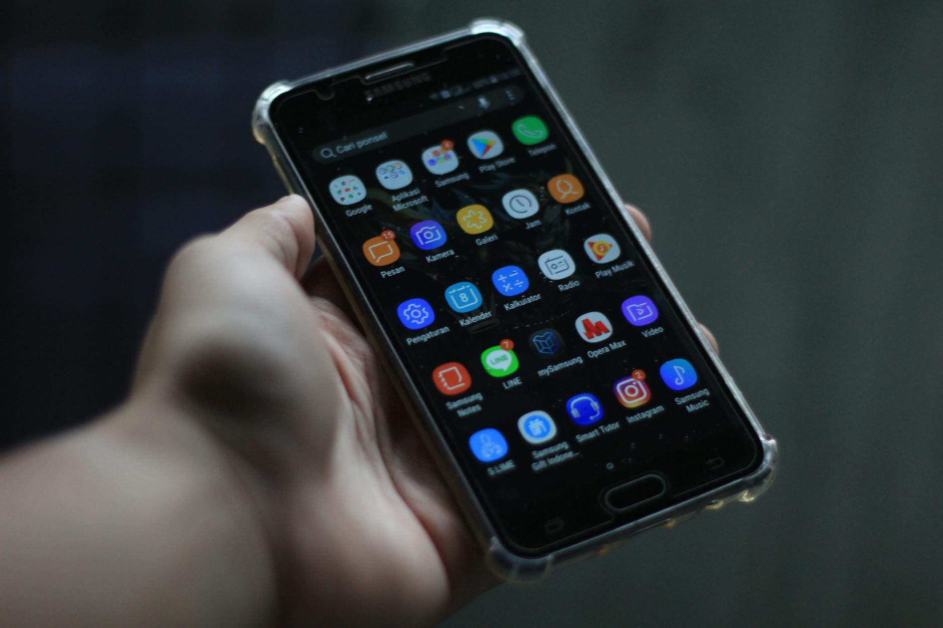 hand holding android phone with bright screen showing social media
