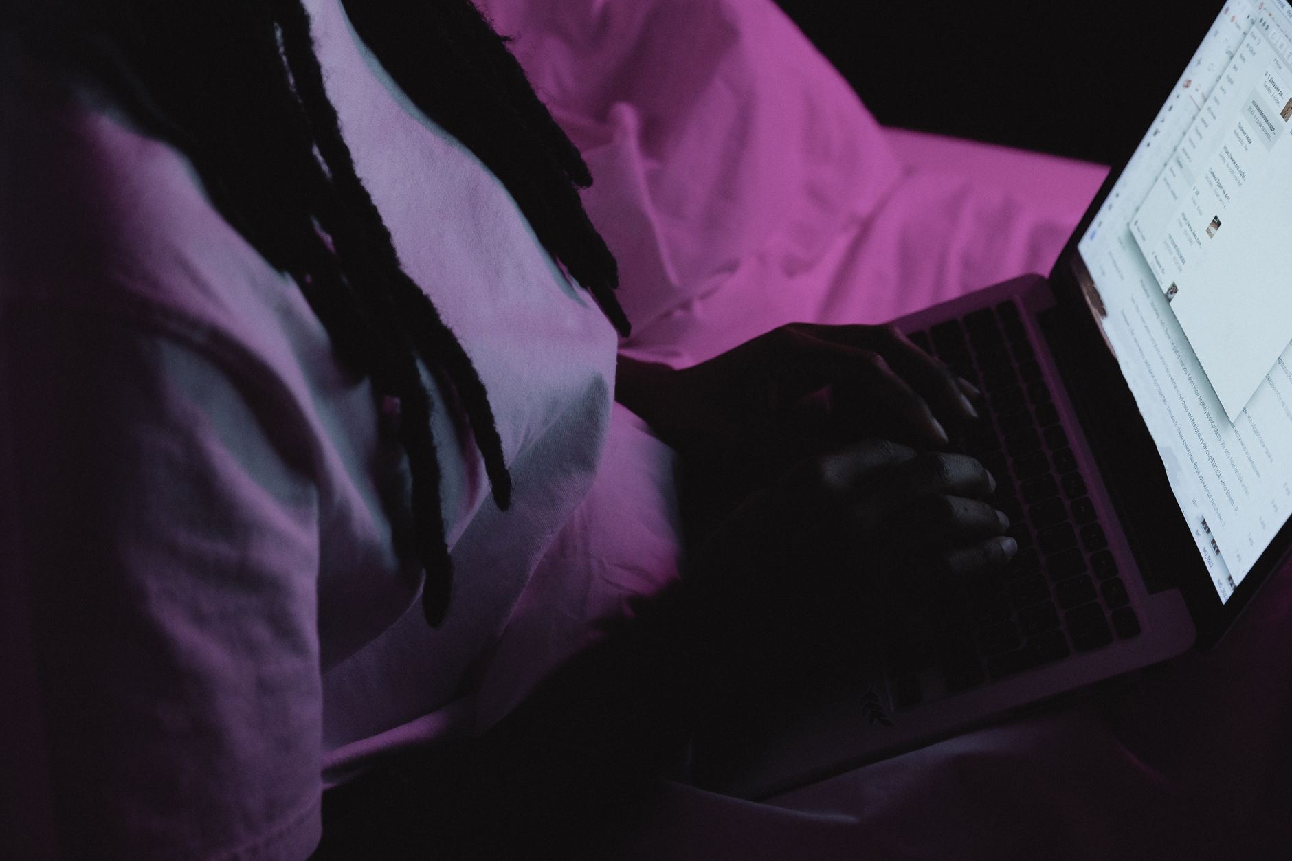 person typing on laptop keyboard in dark room