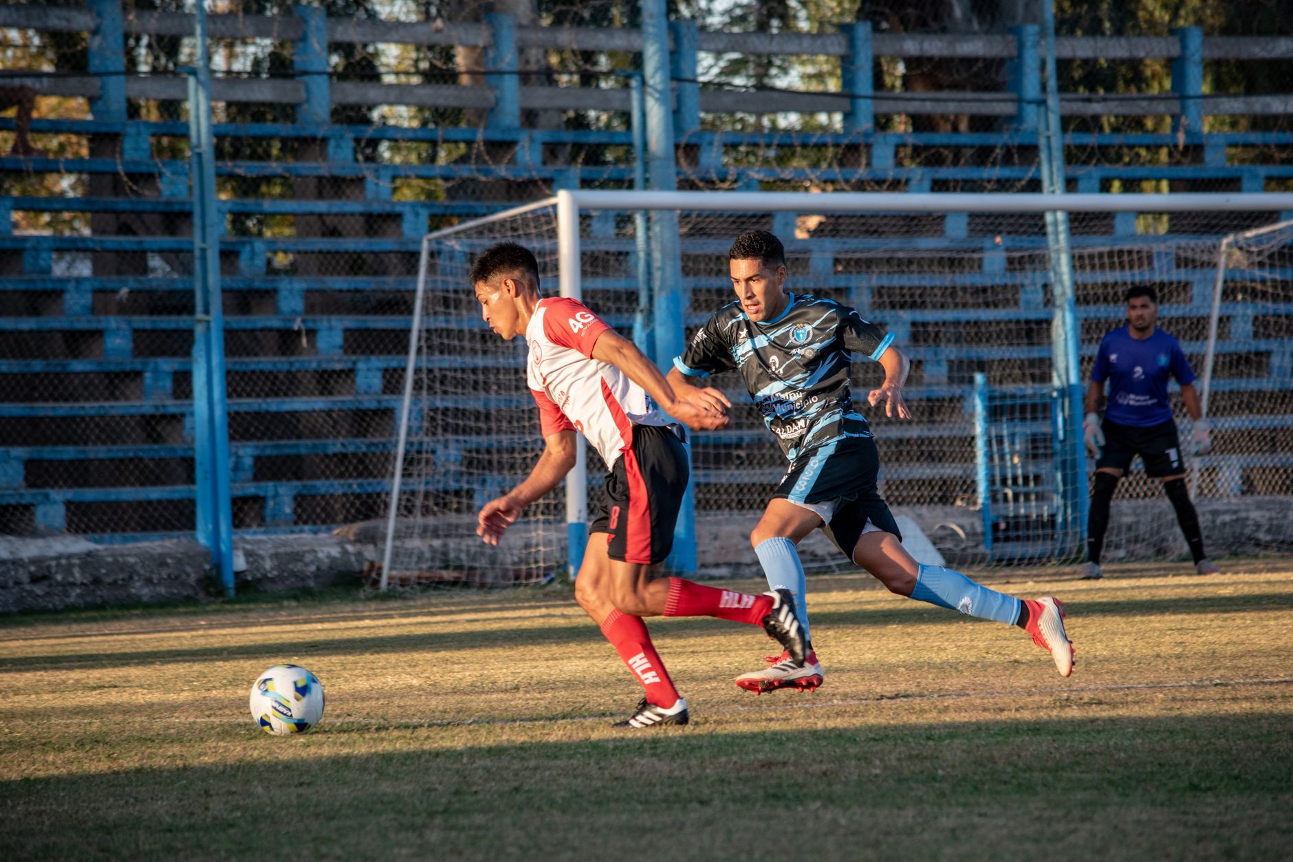 football players competing for ball on field during sunset