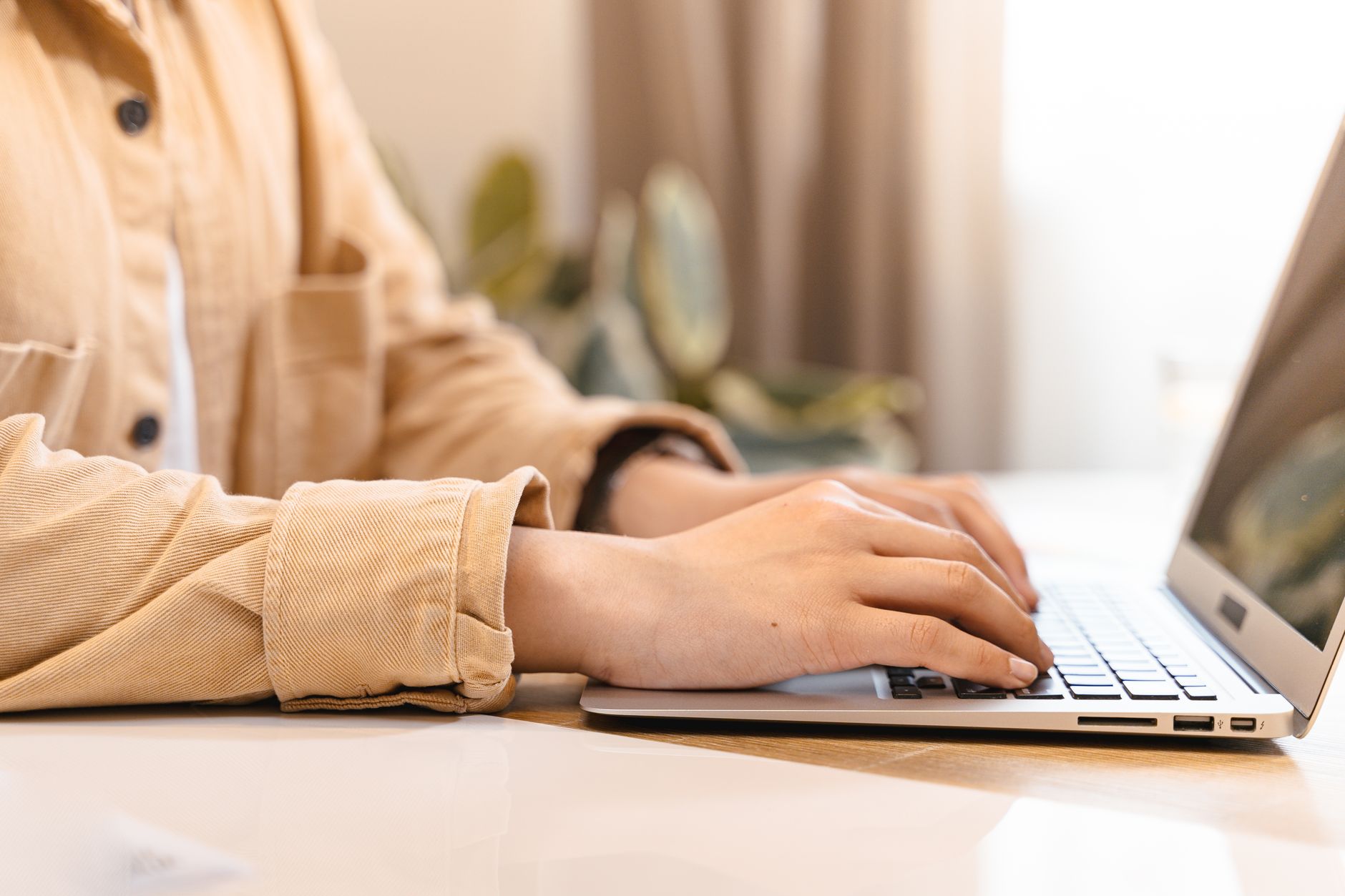 person typing on laptop keyboard in modern office