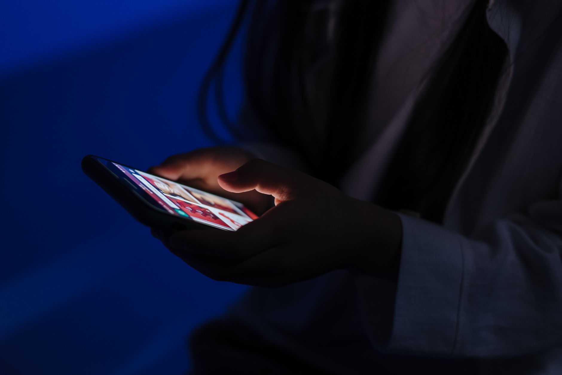 person scrolling social media on smartphone in dim room