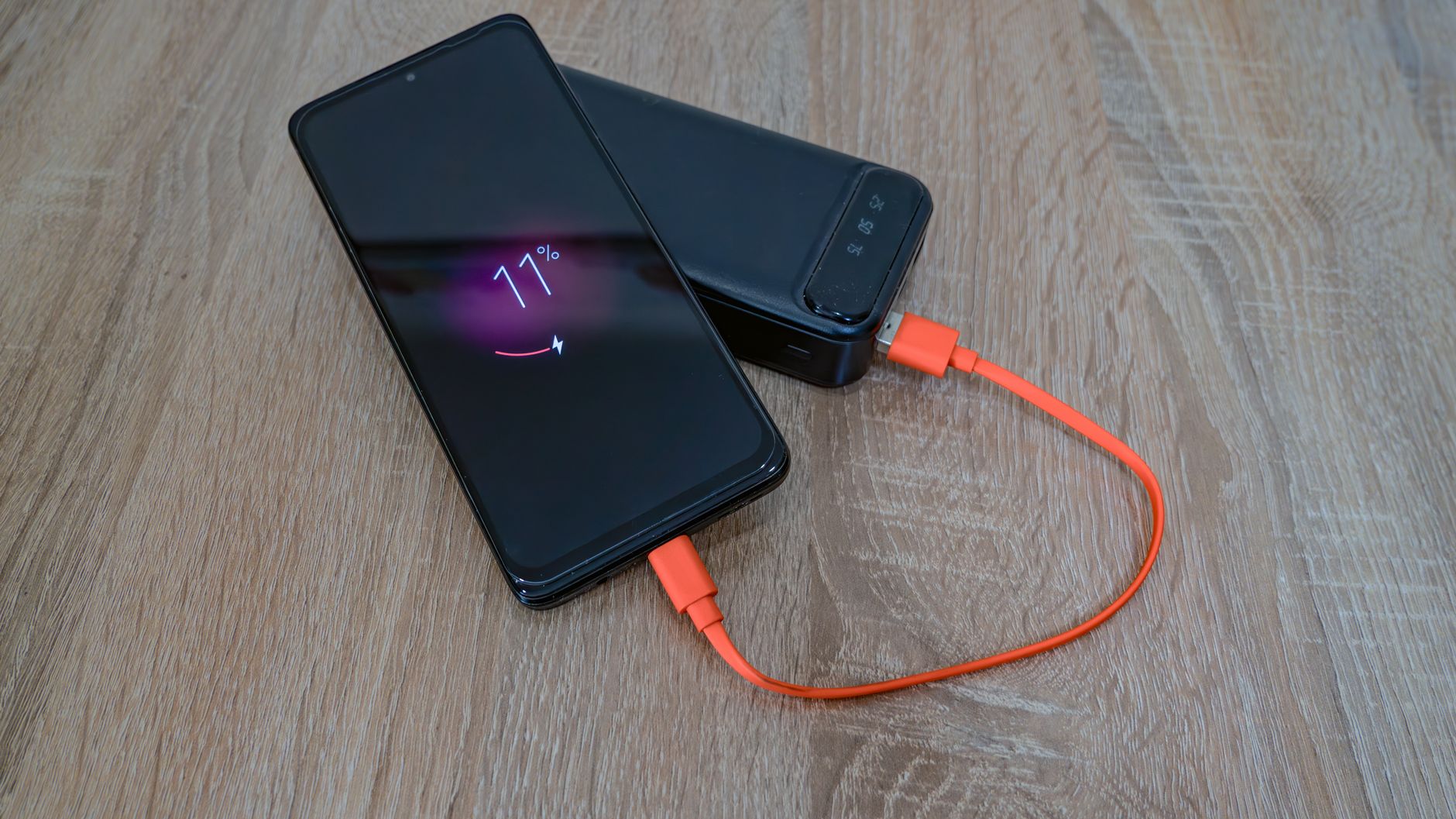 hand holding smartphone charging cable night